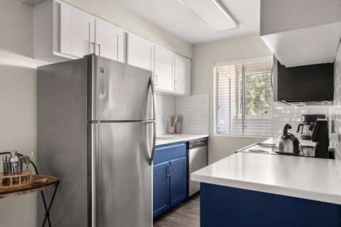 a kitchen with stainless steel refrigerator and white counter tops and blue cabinets