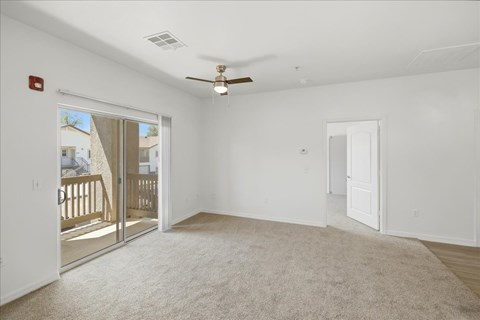 A spacious room with a ceiling fan and a carpeted floor.