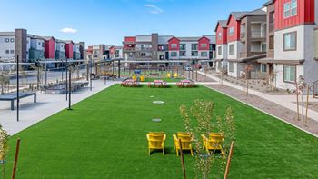 A grassy area with yellow chairs and a playground in the background.