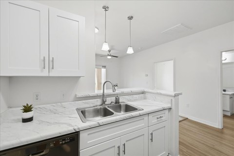 A kitchen with white cabinets and a marble countertop.