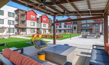 A patio area with a yellow chair and a red couch.