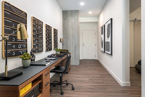 A black and white kitchen with a long counter and a chalkboard on the wall.