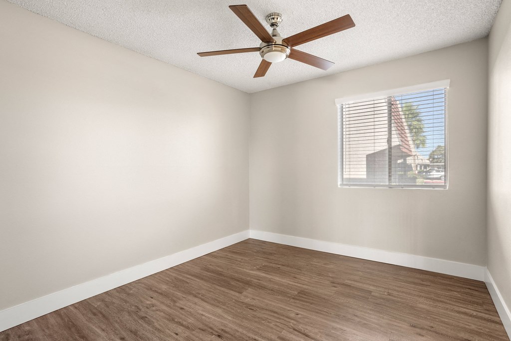 an empty room with a ceiling fan and a window