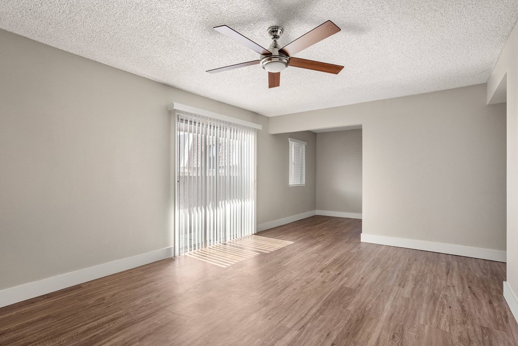 an empty living room with a ceiling fan