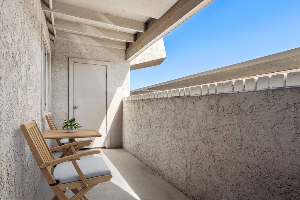 a wooden chair with a blue cushion sits on a balcony with a white door in the background