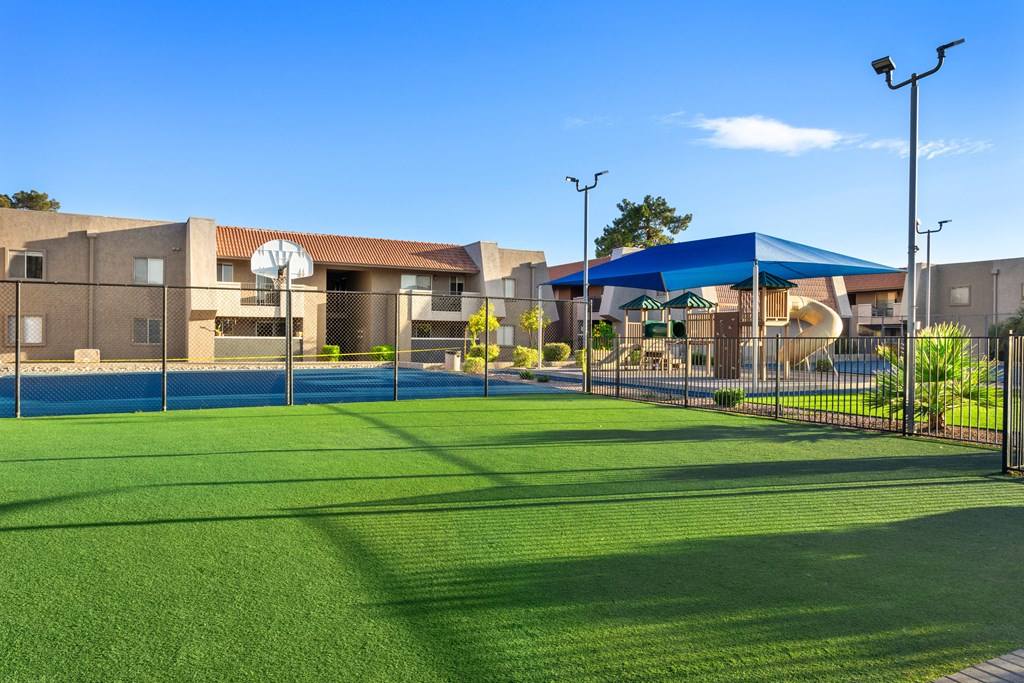 a tennis court with umbrellas and buildings in the background