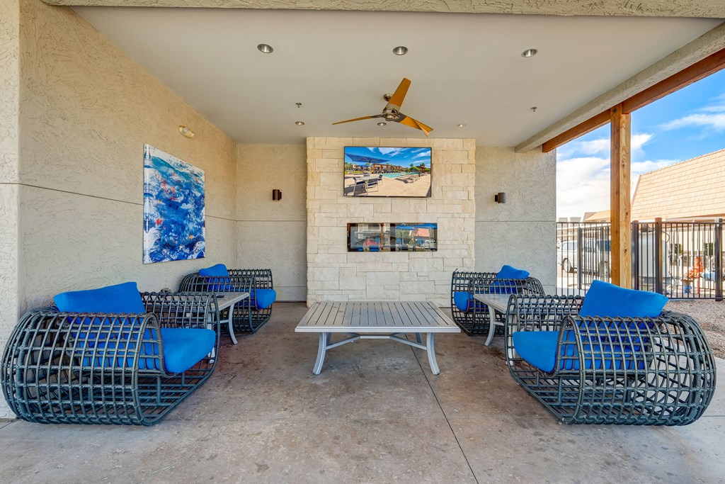 a patio with blue chairs and a table and a ceiling fan