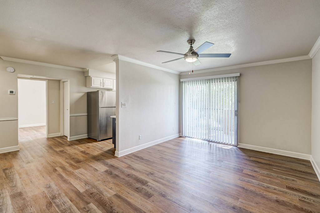 an empty living room with wood flooring and a ceiling fan