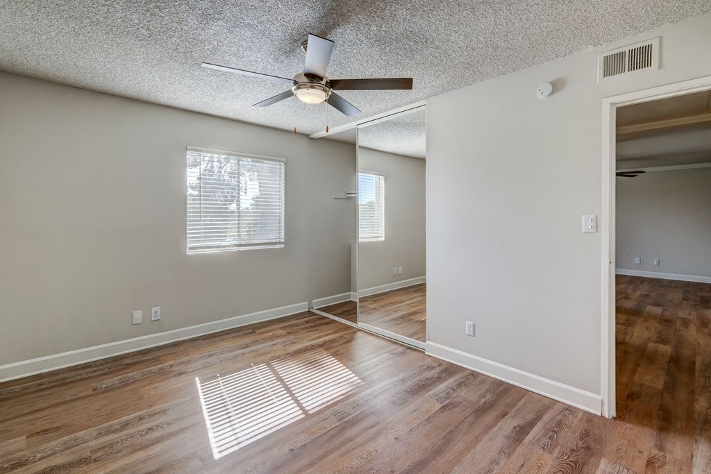 the living room and dining room of an empty house with a ceiling fan