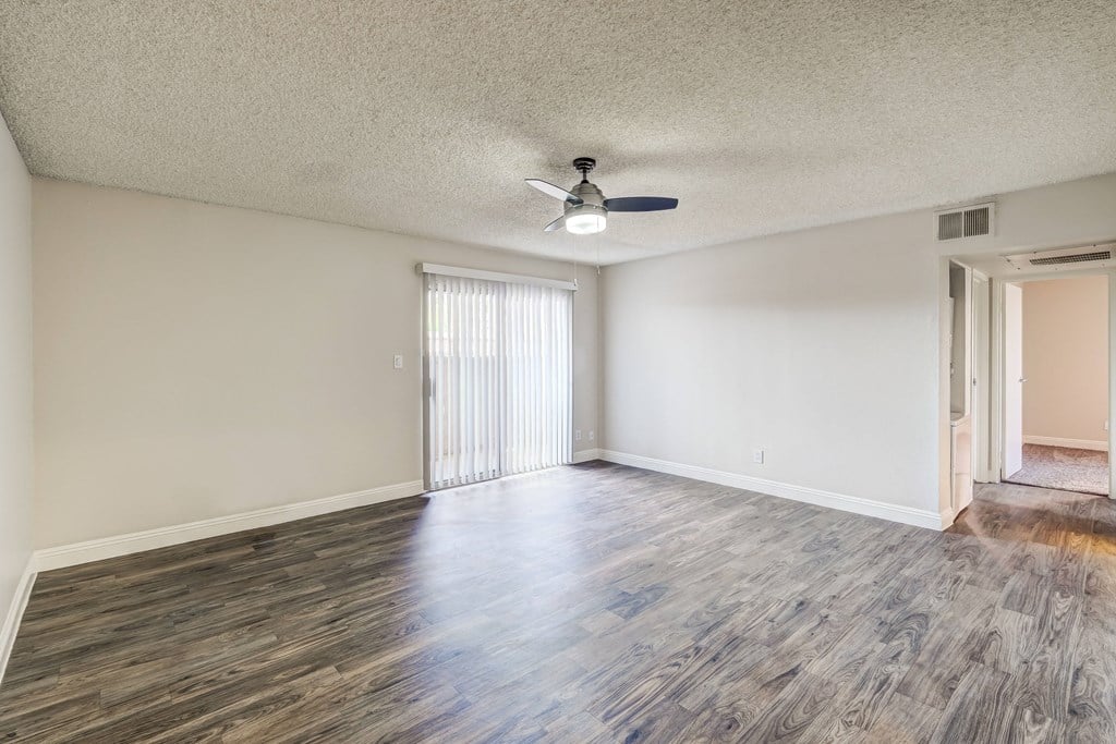 an empty living room with wood flooring and a ceiling fan