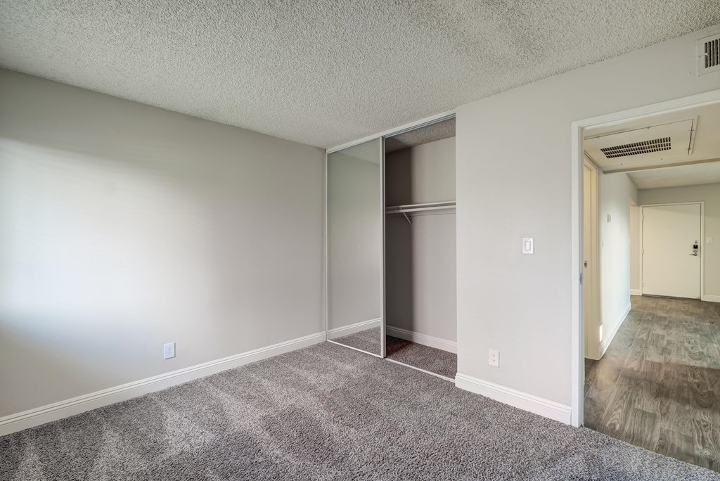 an empty living room with a closet in the corner