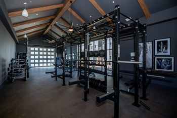 A gym with a variety of equipment including a squat rack, bench, and weights.