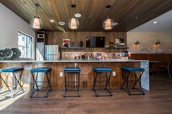 Four blue bar stools are in front of a bar.