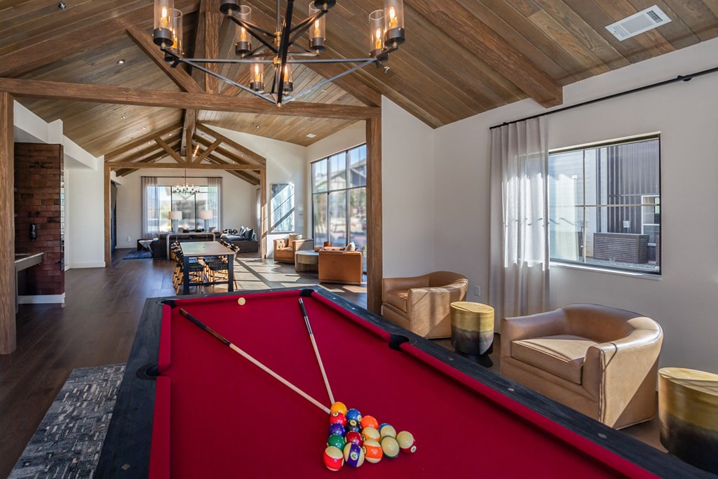 A pool table with a red cloth and a pool cue with a colorful pool ball on it.
