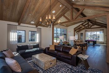 A large, open-concept living room with wooden beams and a variety of seating options.