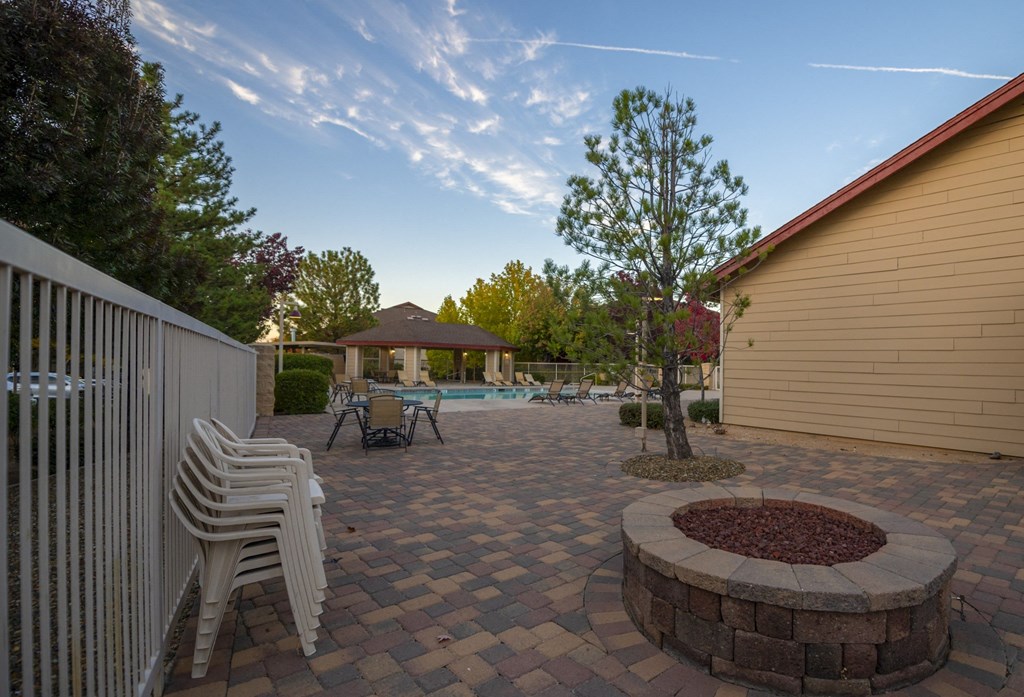 a patio with a fire pit and a pool in a backyard