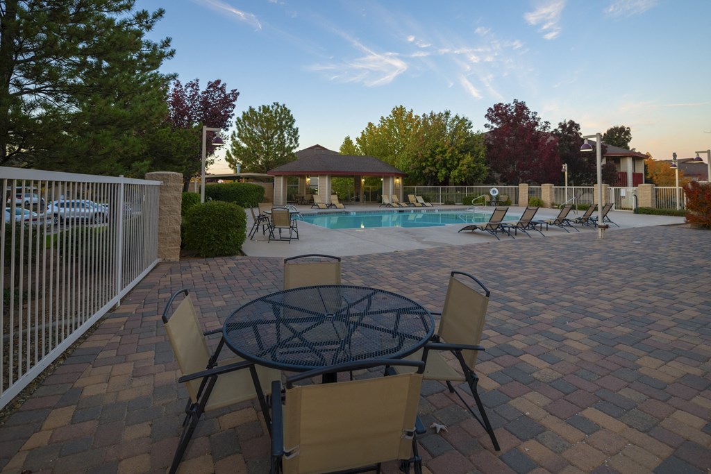 a patio with a table and chairs next to a pool