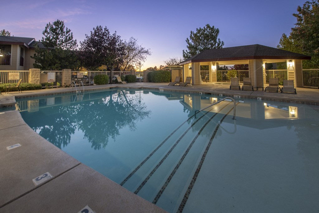 a swimming pool with a house in the background at dusk