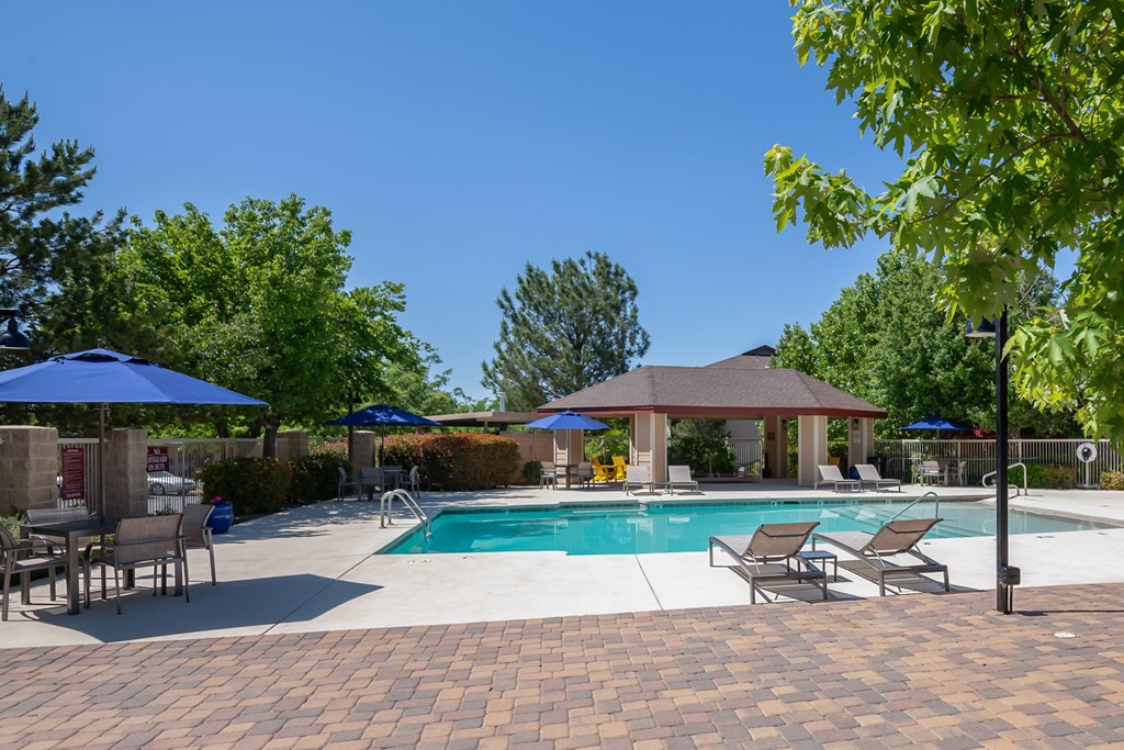 a swimming pool with patio furniture and umbrellas