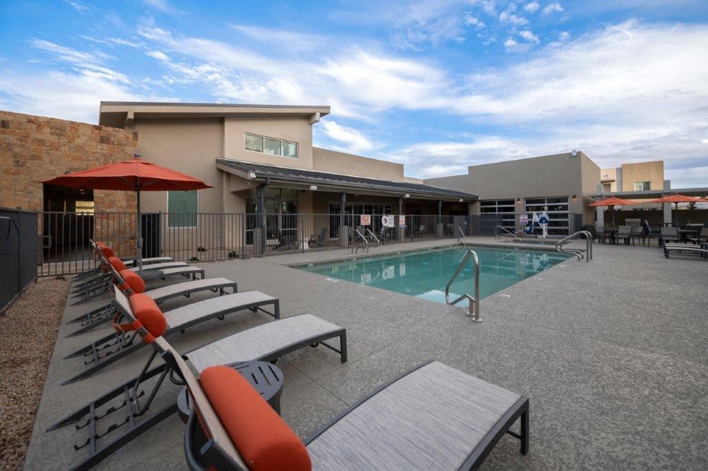 a pool with chairs and a building in the background at Inspiration Apartments, Cottonwood, AZ