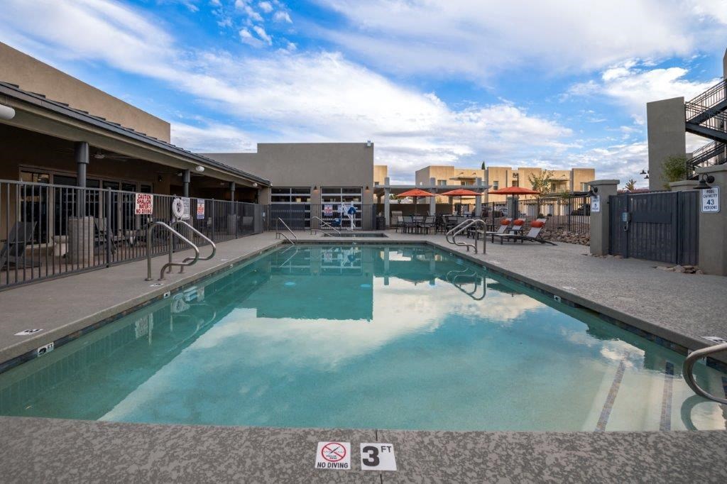 a swimming pool at a hotel with a blue cloudy sky at Inspiration Apartments, Cottonwood, Arizona