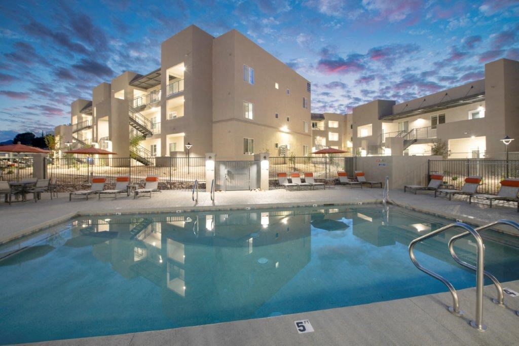 a swimming pool with palm trees in front of a building at Inspiration Apartments, Cottonwood