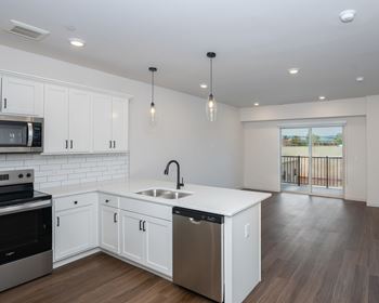 A modern kitchen with white cabinets and stainless steel appliances.