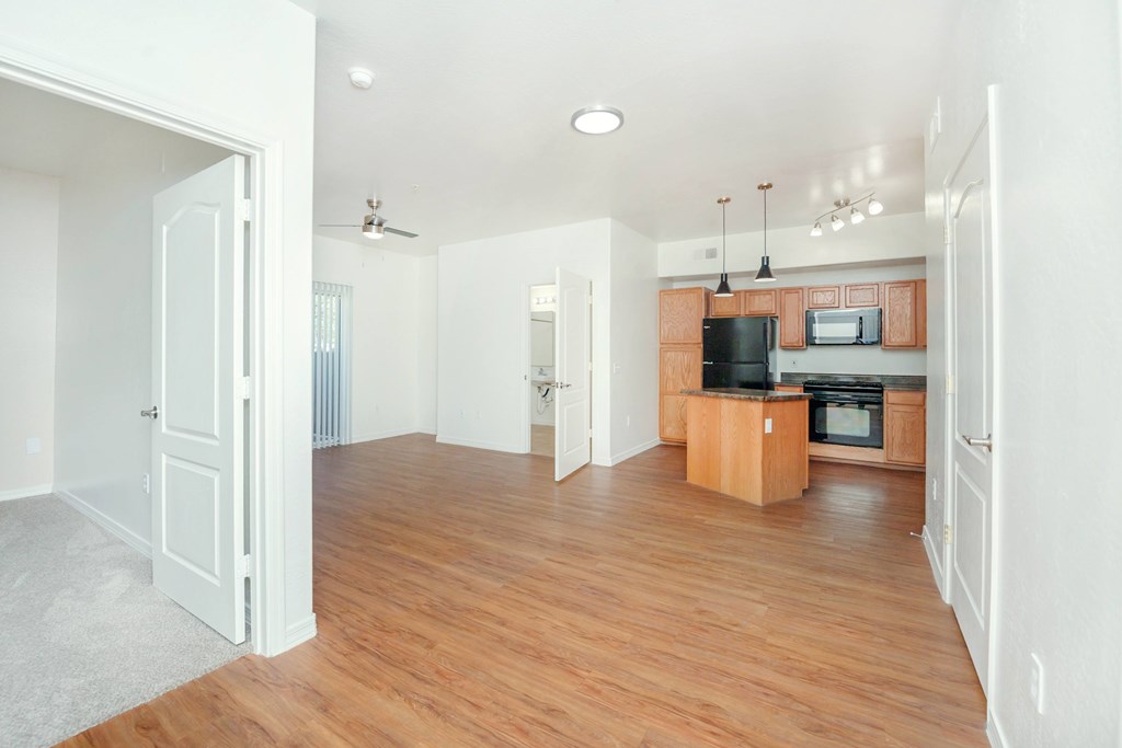 A spacious kitchen with wooden floors and white walls.