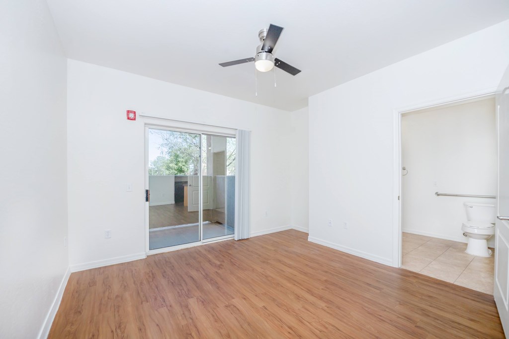 A room with a ceiling fan and a sliding glass door leading to a balcony.