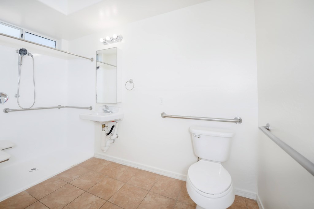 A white toilet in a bathroom with a white sink and a shower.