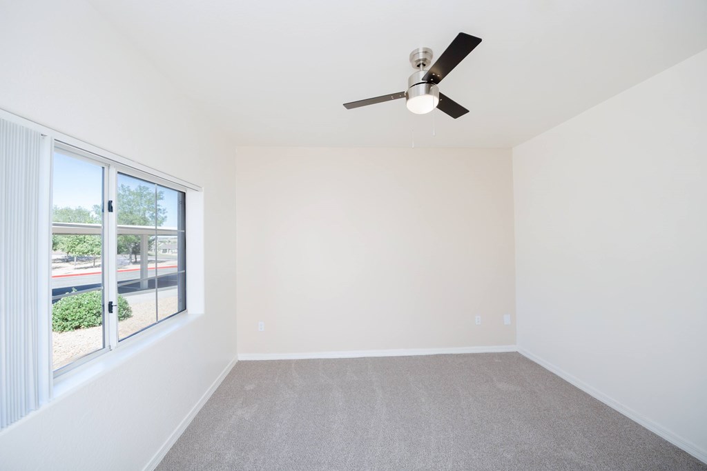 A room with a ceiling fan and a large window.