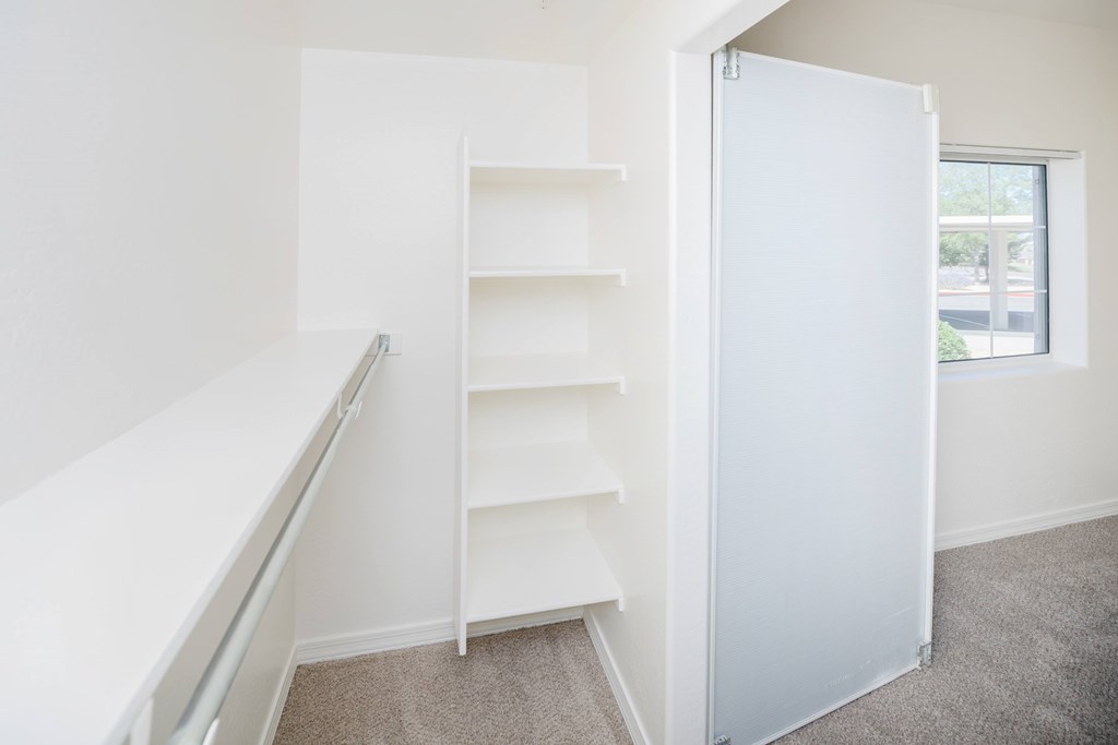 A white closet with shelves and a window.