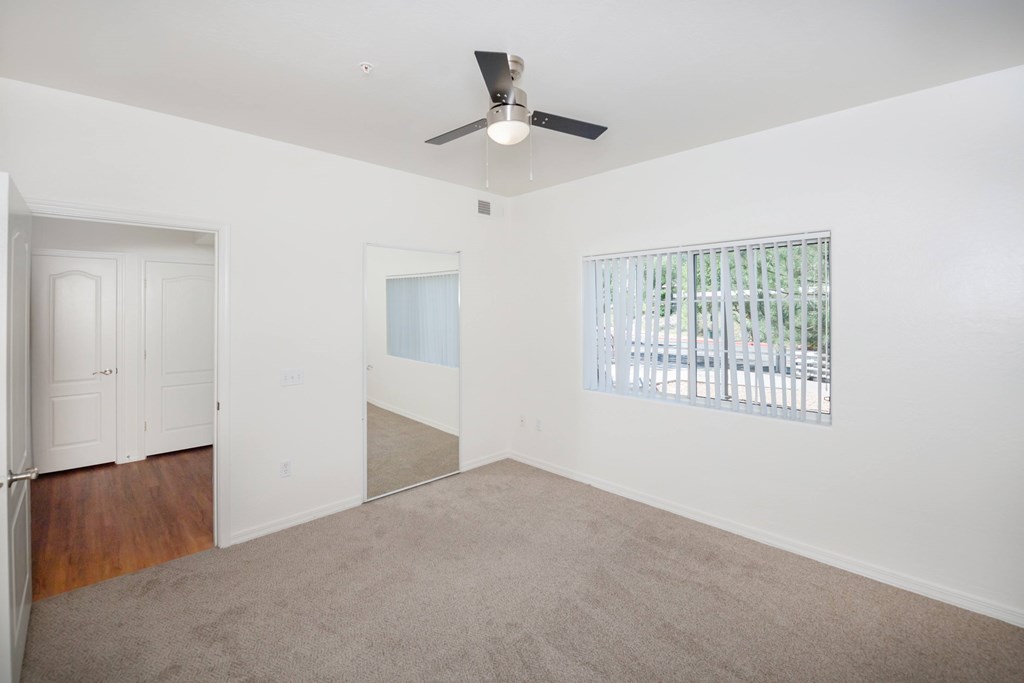 A room with a ceiling fan and a window with blinds.