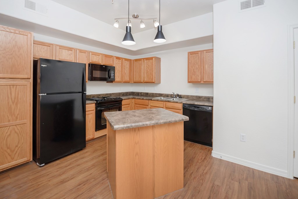 A kitchen with wooden cabinets and a black refrigerator.