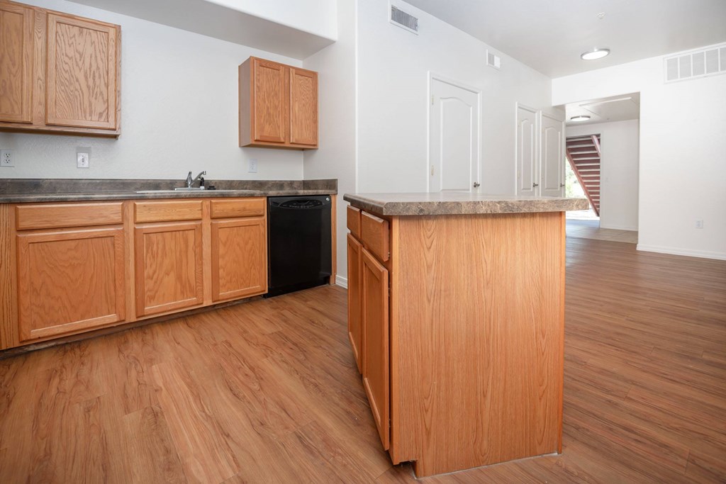A kitchen with wooden cabinets and a black dishwasher.