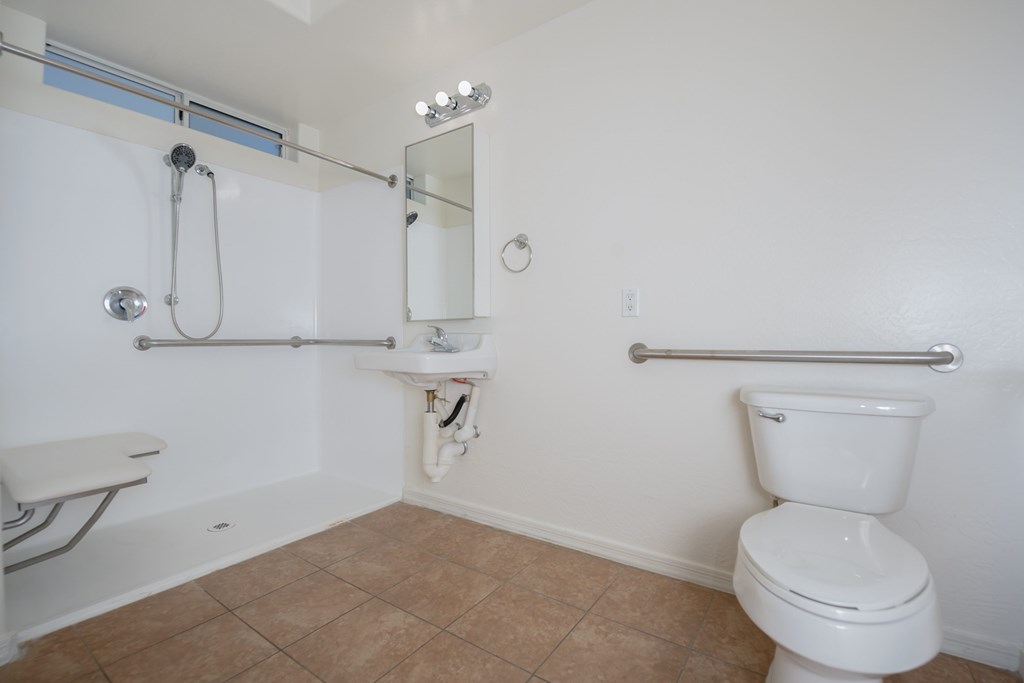 A white toilet sits in a bathroom with a white tub and shower.