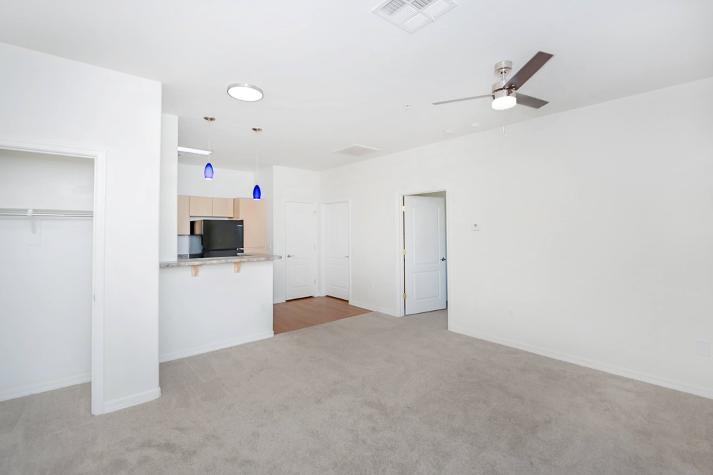 A spacious room with a ceiling fan and a flat screen TV mounted on the wall.