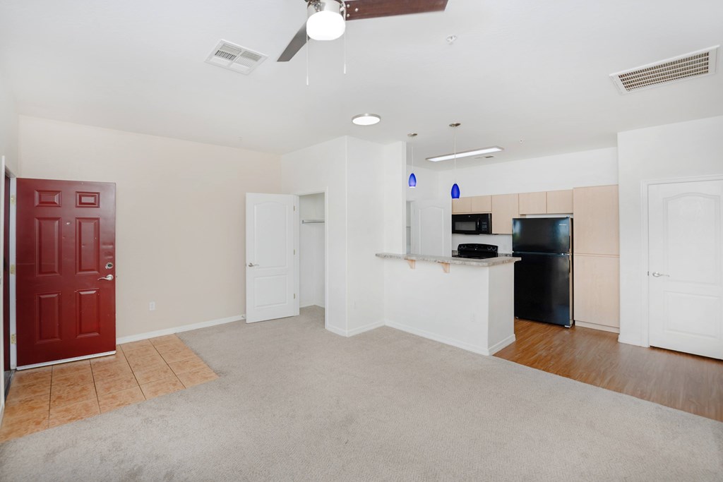 A room with a red door and a black fridge.