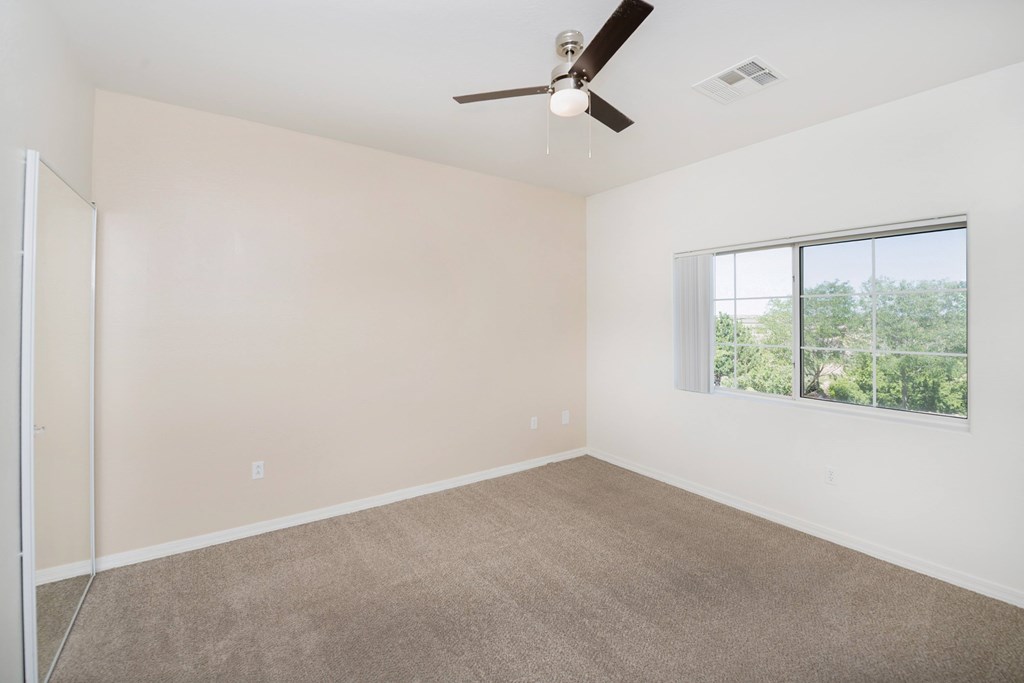 Empty room with a ceiling fan and a window.