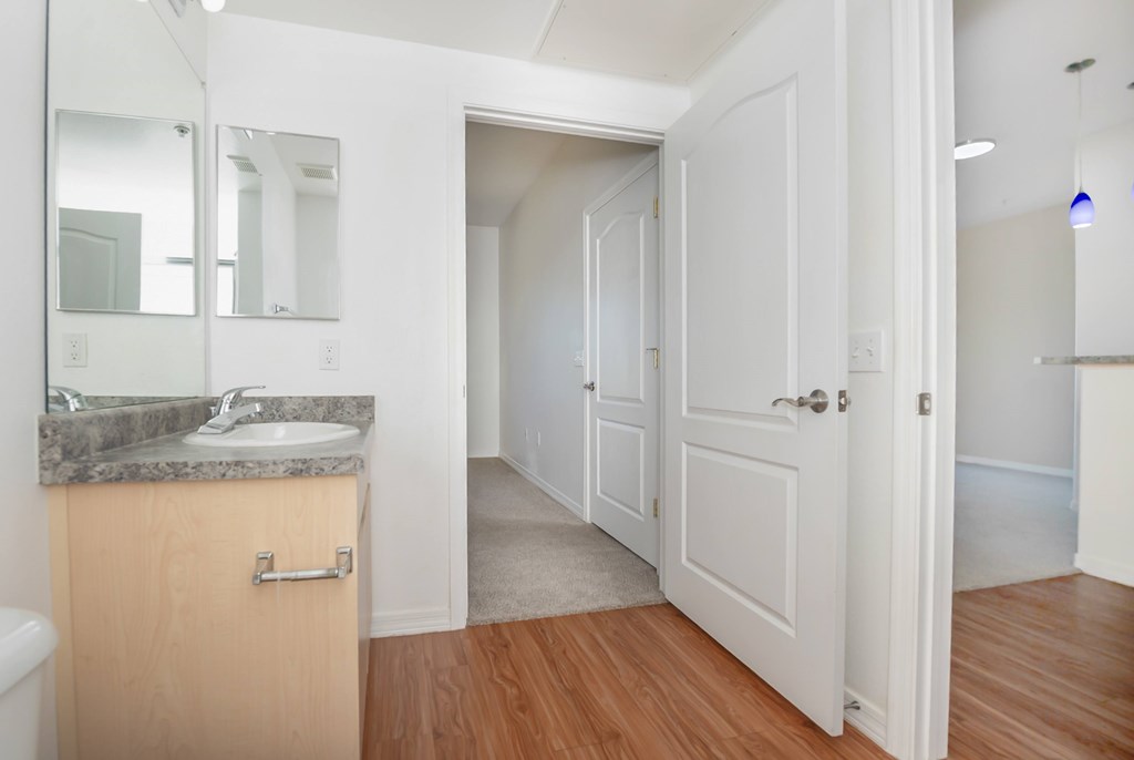 A bathroom with a sink, mirror, and wooden floors.