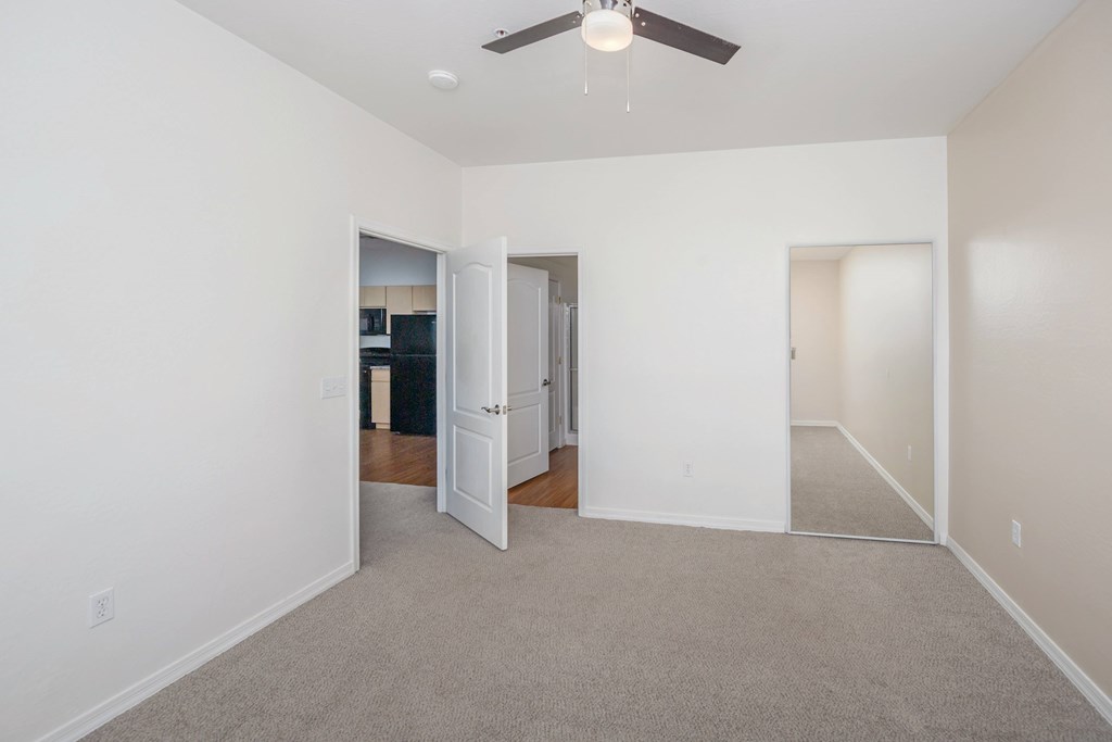 A room with a ceiling fan and carpeted floor.