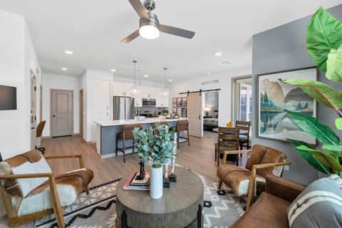 A living room with a ceiling fan and a coffee table with a vase on it.