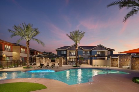 A swimming pool surrounded by palm trees and apartment buildings.