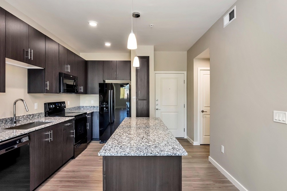 A kitchen with a granite countertop and dark wood cabinets. at The Premiere at Dana Park, Mesa