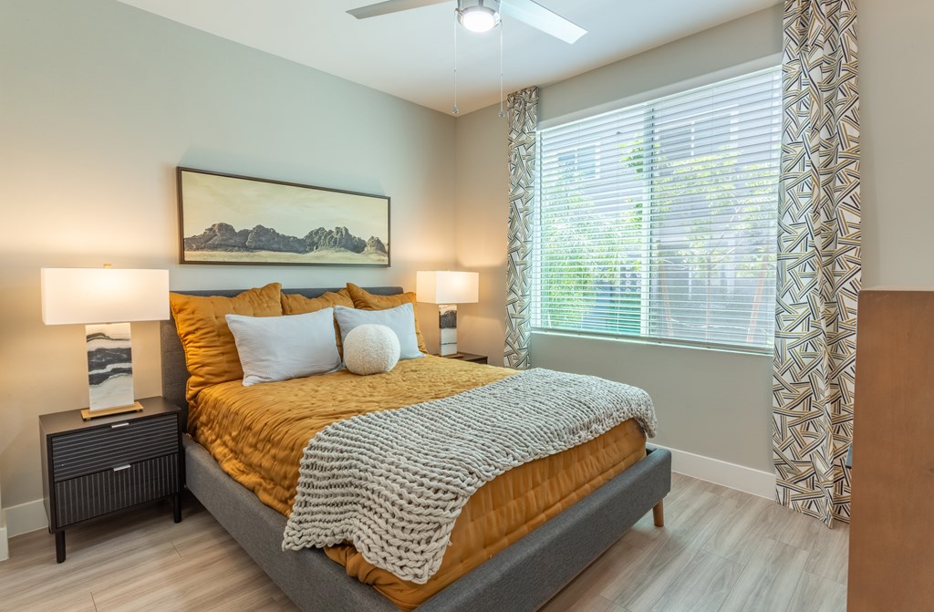 A bedroom with a bed, two lamps, and a painting on the wall.