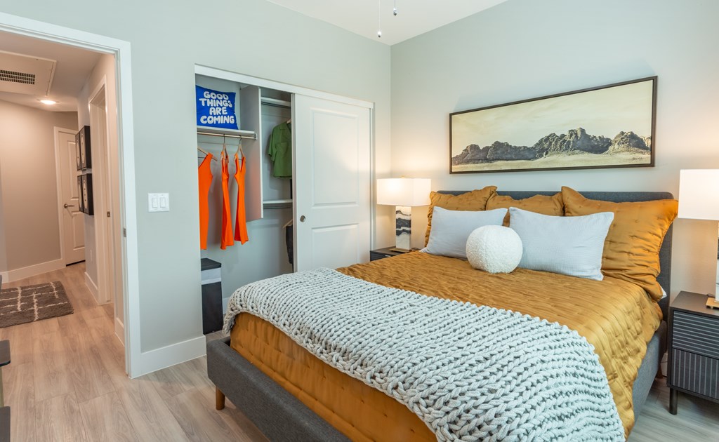 North Phoenix, AZ Luxury Apartments With In-Unit Washer And Dryer - The Amelia - Modern Bedroom With Wood-Style Vinyl Plank Flooring, Sliding Closet, And Central Air Conditioning & Heating.