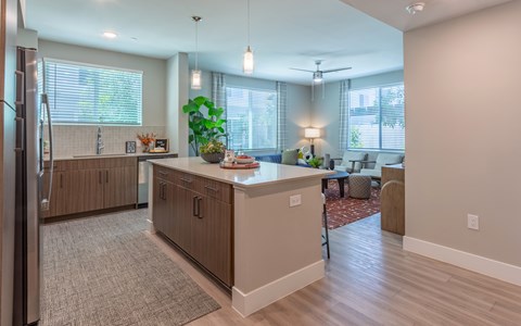 A kitchen with a refrigerator on the left and a dining area with a table and chairs.
