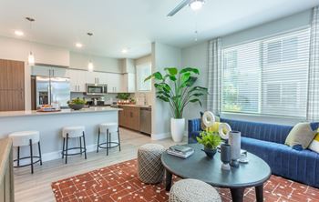 A modern living room with a kitchen in the background.