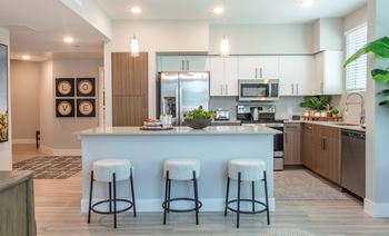 A kitchen with a white island and three bar stools.