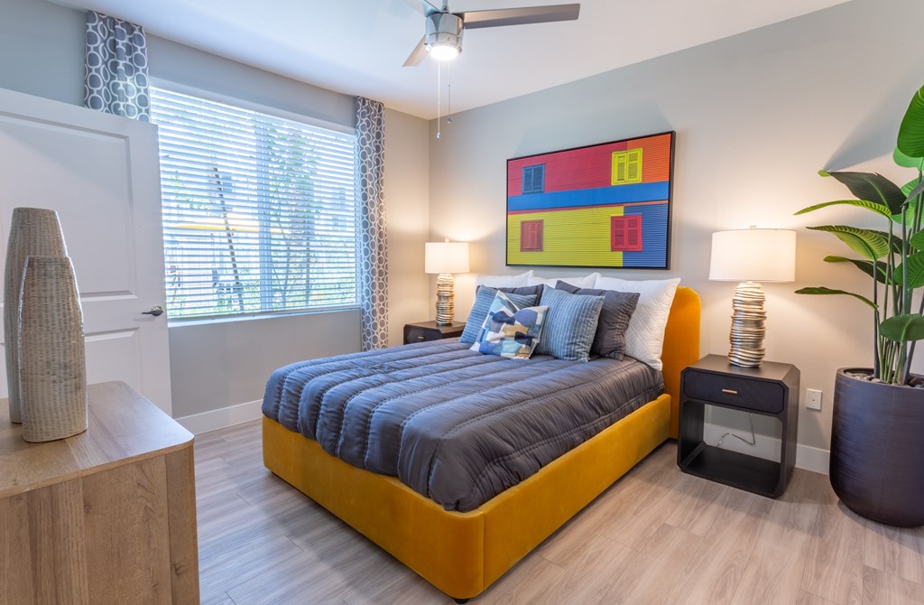 A bedroom with a bed, nightstand, and a painting on the wall.